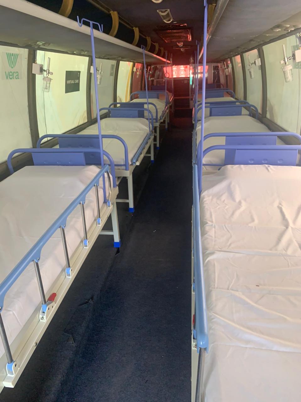 Inside the b.SOZO Critical Care bus before deployment · rows of hospital beds with IV stands and Vera logo visible on the wall · virtual care label